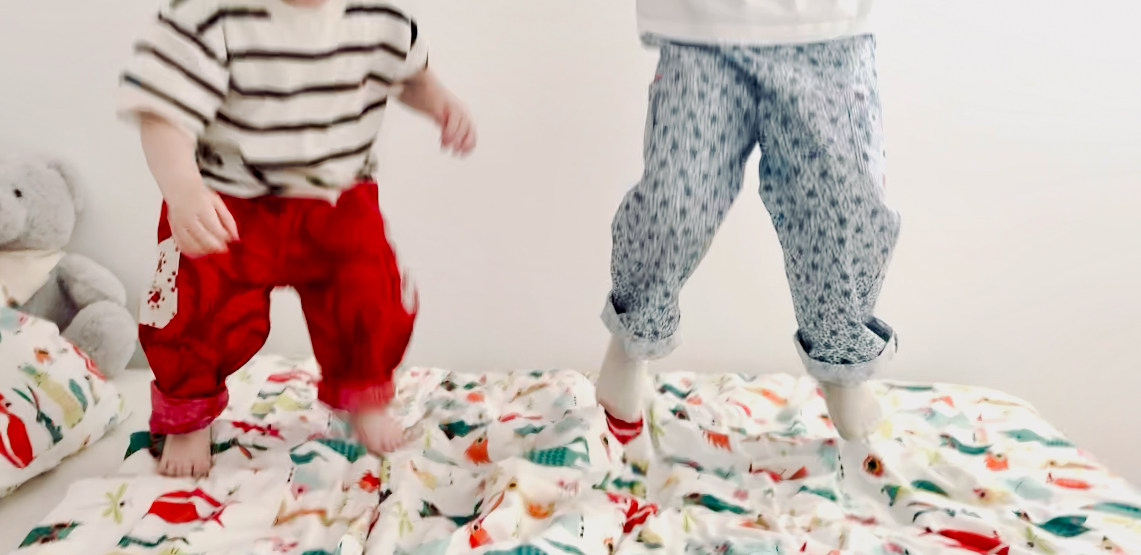 Two children standing on a colorful quilt with animal patterns.